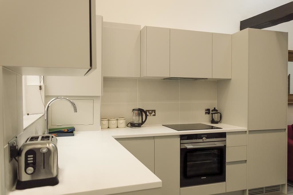 Una cocina moderna con armarios blancos, horno empotrado, un lavabo y un tostador.