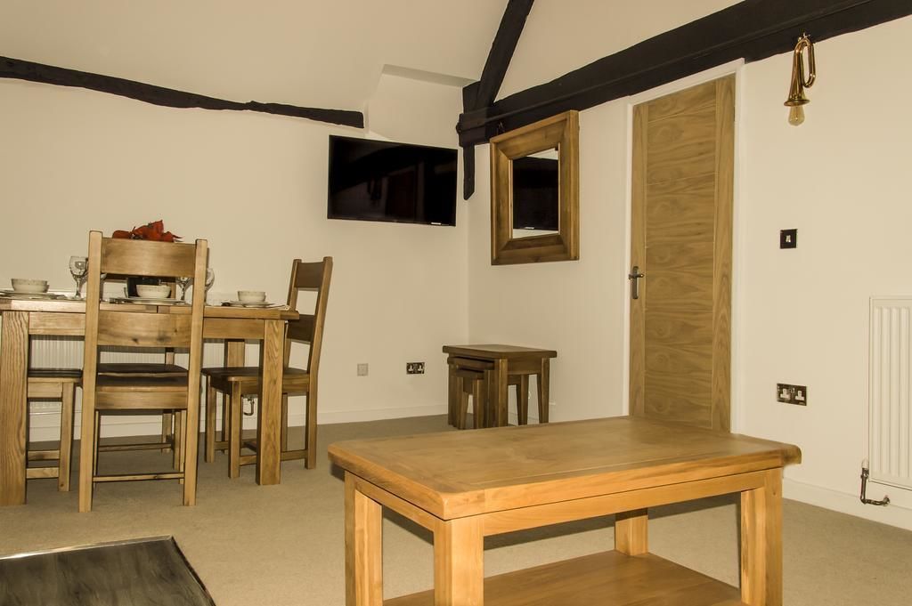 A dining area with a wooden table and chairs, a television mounted on the wall, and a wooden door.