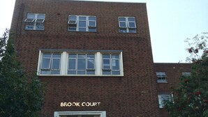 Tiilestä rakennettu rakennus, jonka sisäänkäynnin yläpuolella on kyltti, jossa lukee ”BROOK COURT”.