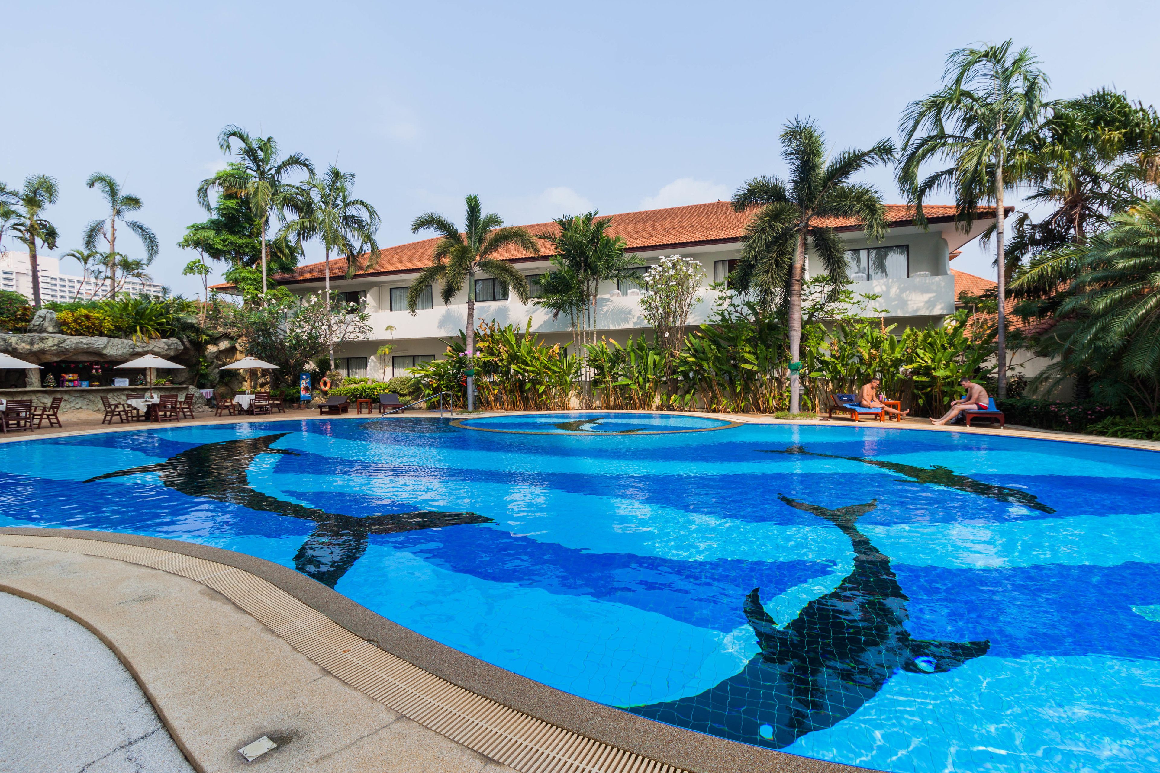 A swimming pool with a shark design, surrounded by palm trees and lounge chairs.