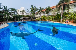 A swimming pool with dolphins, surrounded by palm trees and a building with a tiled roof. - View Talay Residence 1 by PSR (Pattaya)