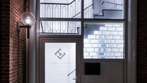 A hotel entrance with a glass door, a metal staircase, and a brick wall. - Hotel Town Living (Ringkobing)