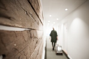Un pasillo con una pared de madera y una persona alejándose con una maleta.