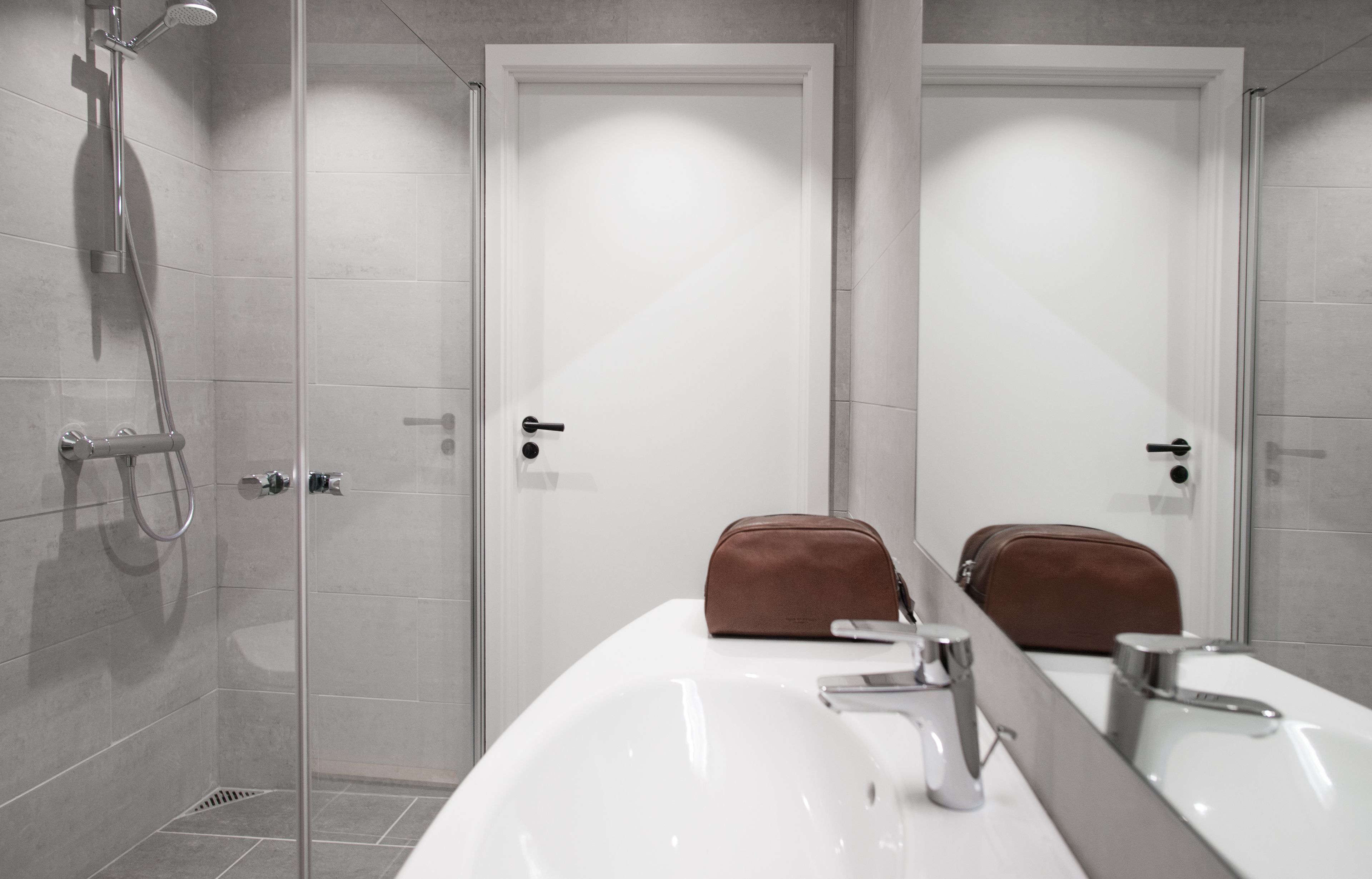 A modern bathroom with a shower, two sinks, and a mirror.