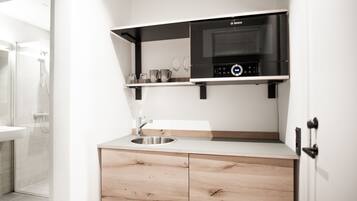 Une cuisine moderne équipée d’un four à micro-ondes Bosch, d’un évier en acier inoxydable et de meubles de rangement en bois.