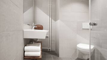 Un baño moderno con un lavamanos blanco, un inodoro y una zona de ducha.