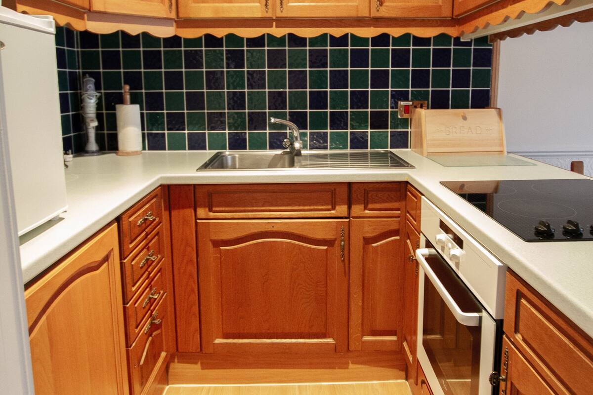 A kitchen with wooden cabinets, a white countertop, a sink, and a stove.