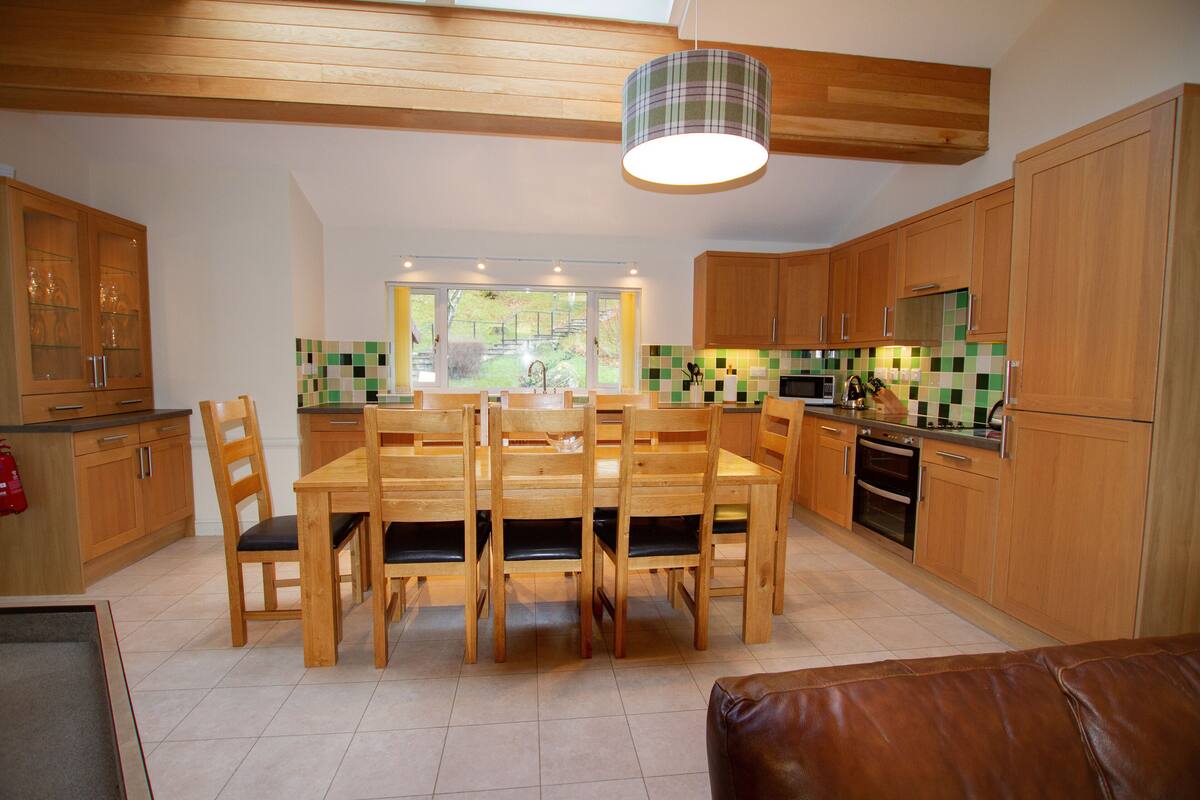 A modern kitchen with wooden cabinets, a dining table with chairs, and a view of the outdoors.