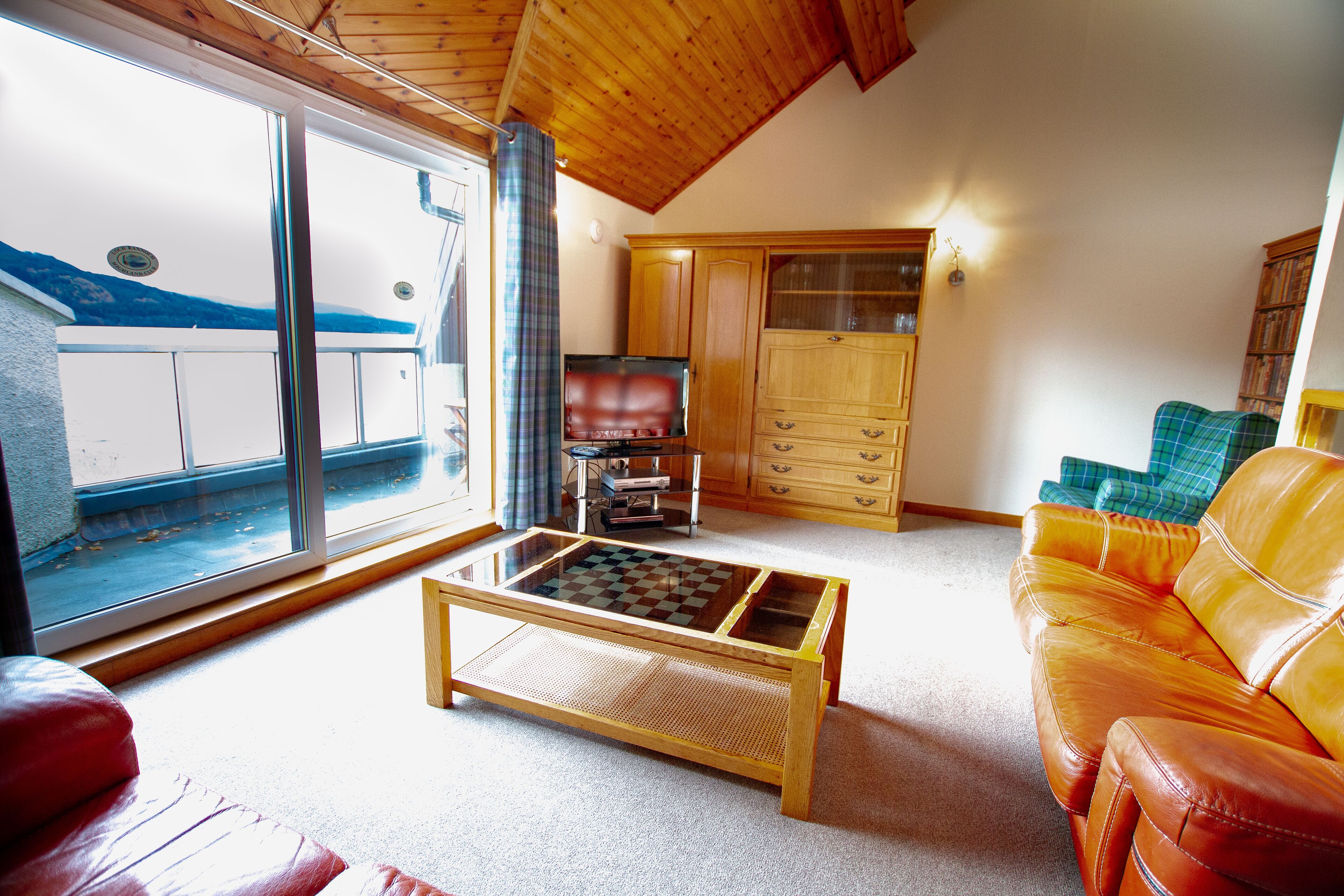 Una sala de estar acogedora con una mesa de centro de madera, un sofá de cuero y un televisor.