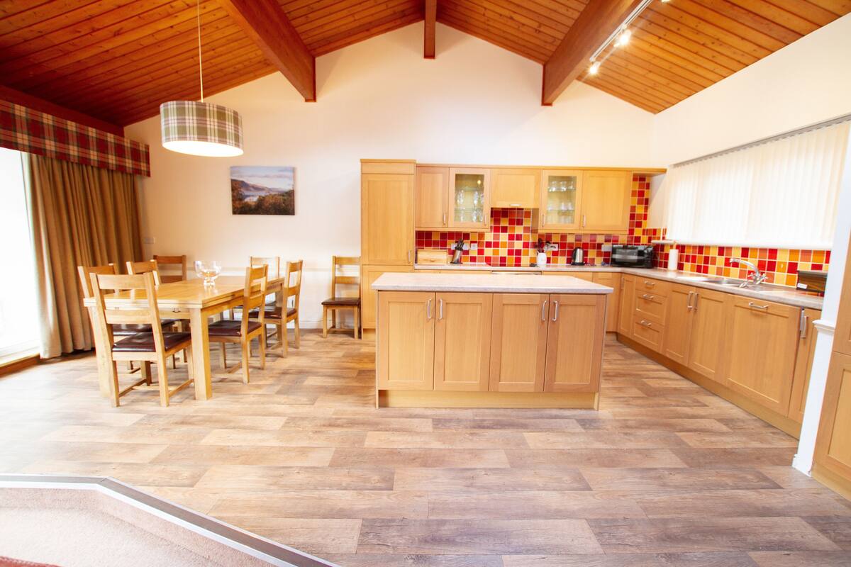 A spacious kitchen with wooden cabinets, a large island, and a herringbone-patterned floor.
