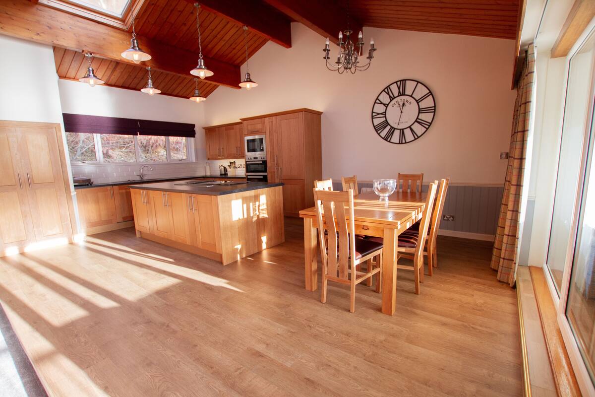 A spacious kitchen with wooden cabinets, a large island, and a dining area with chairs and a table.