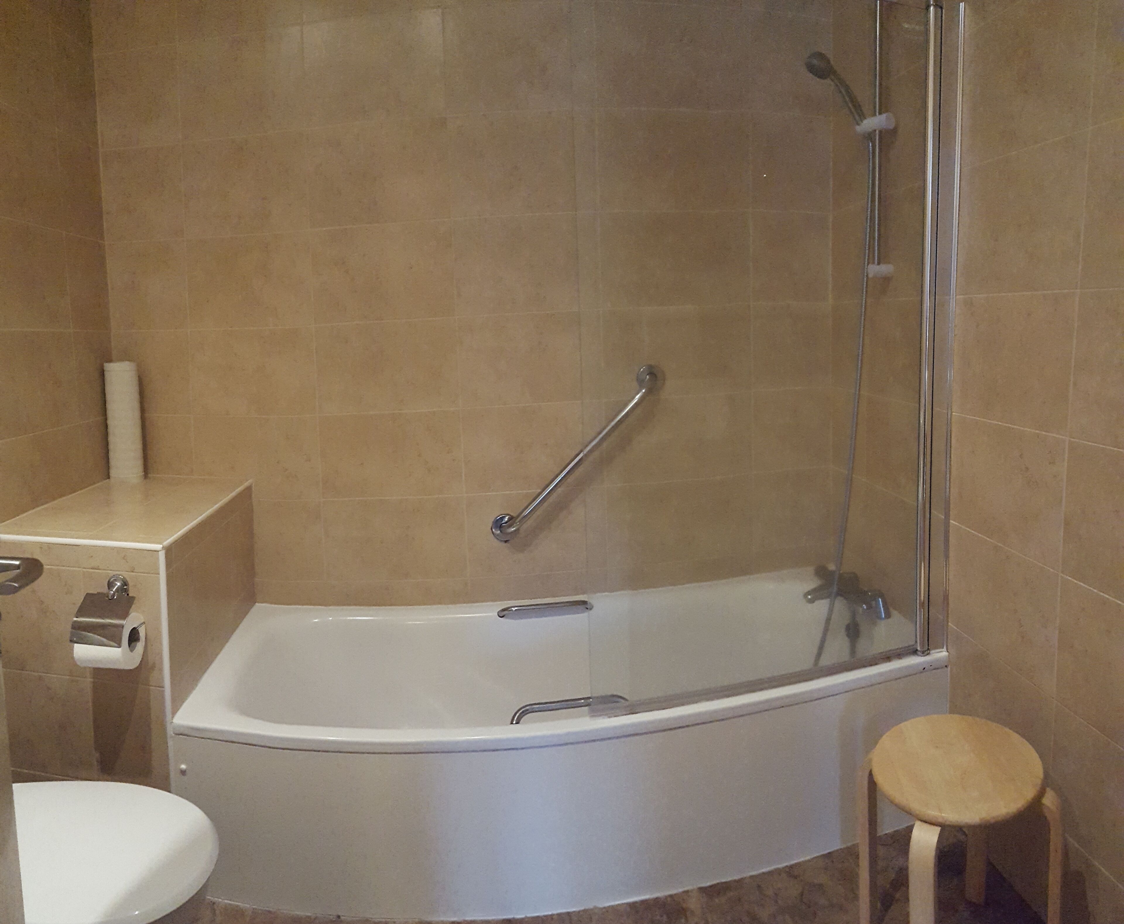 A bathroom with a bathtub, a toilet, and a shower area.
