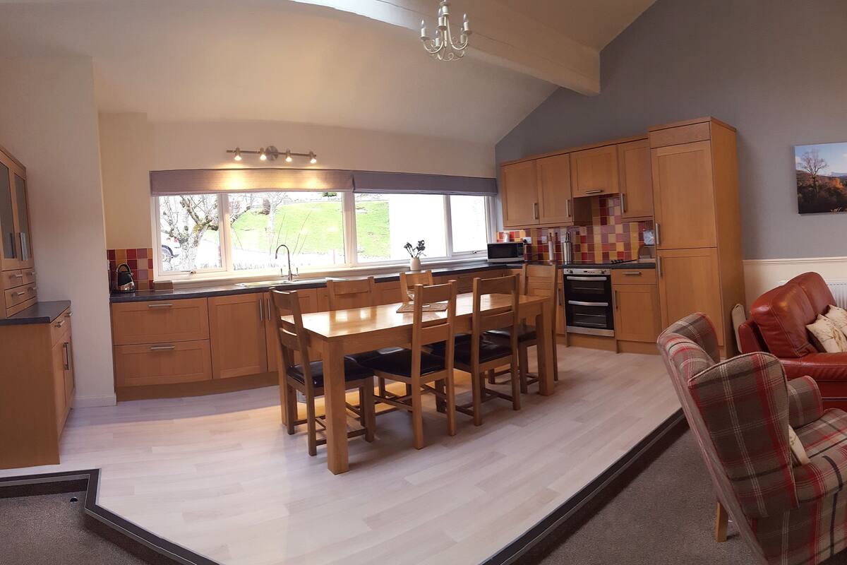 A modern kitchen with wooden cabinets, a dining table, and a view of the outdoors.