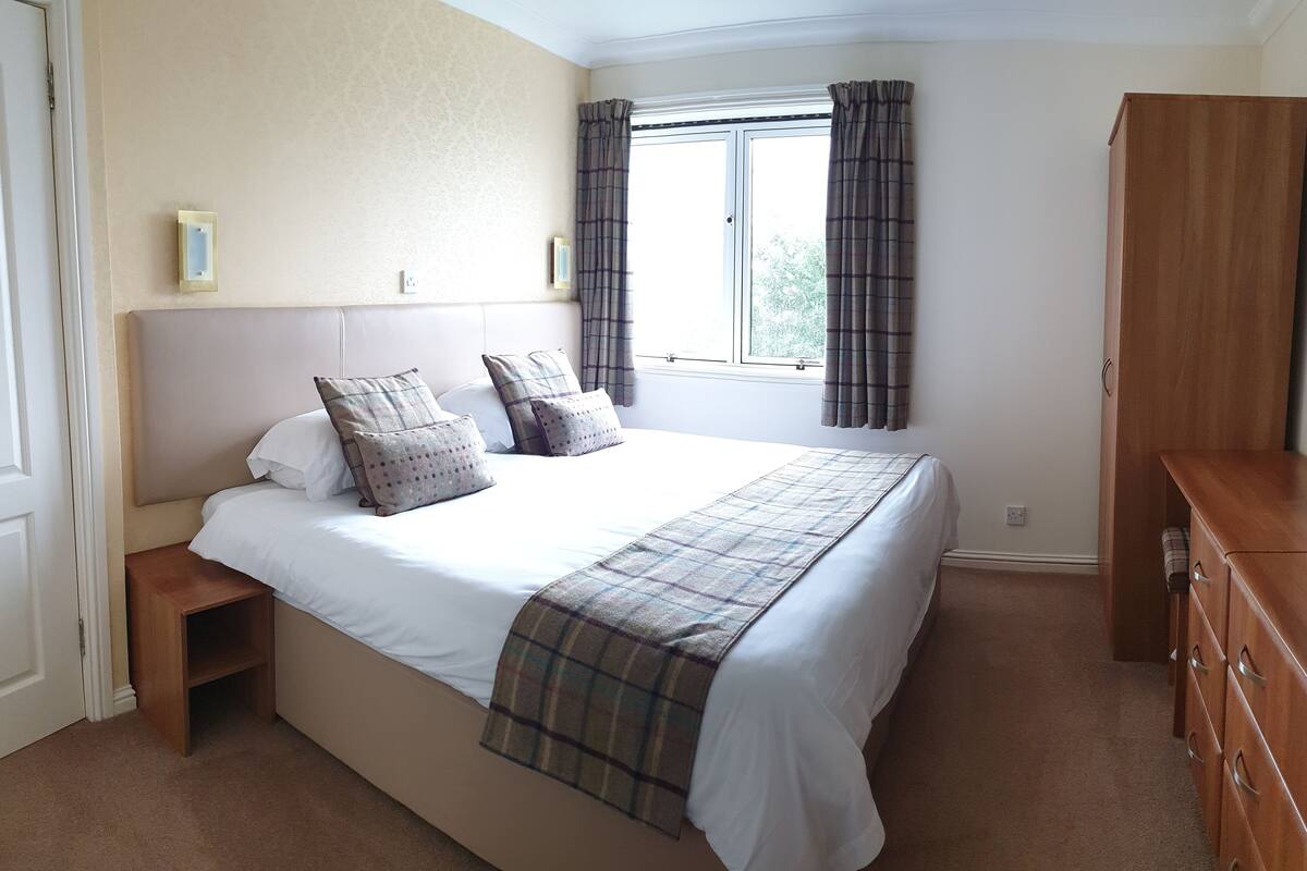 A bedroom with a bed, bedside tables, a wardrobe, and a window with curtains.