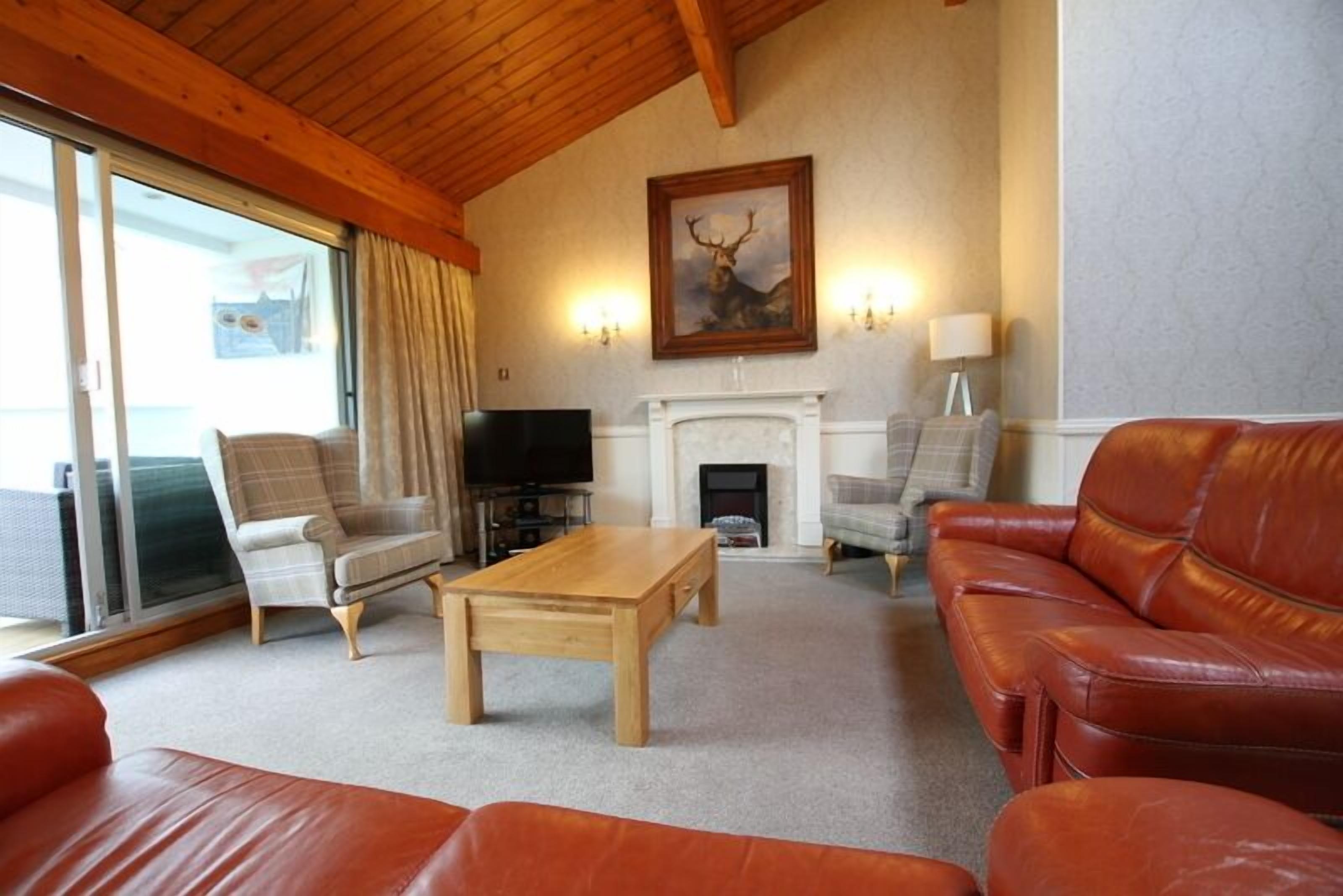 A living room with a fireplace, leather sofas, a coffee table, and a television.