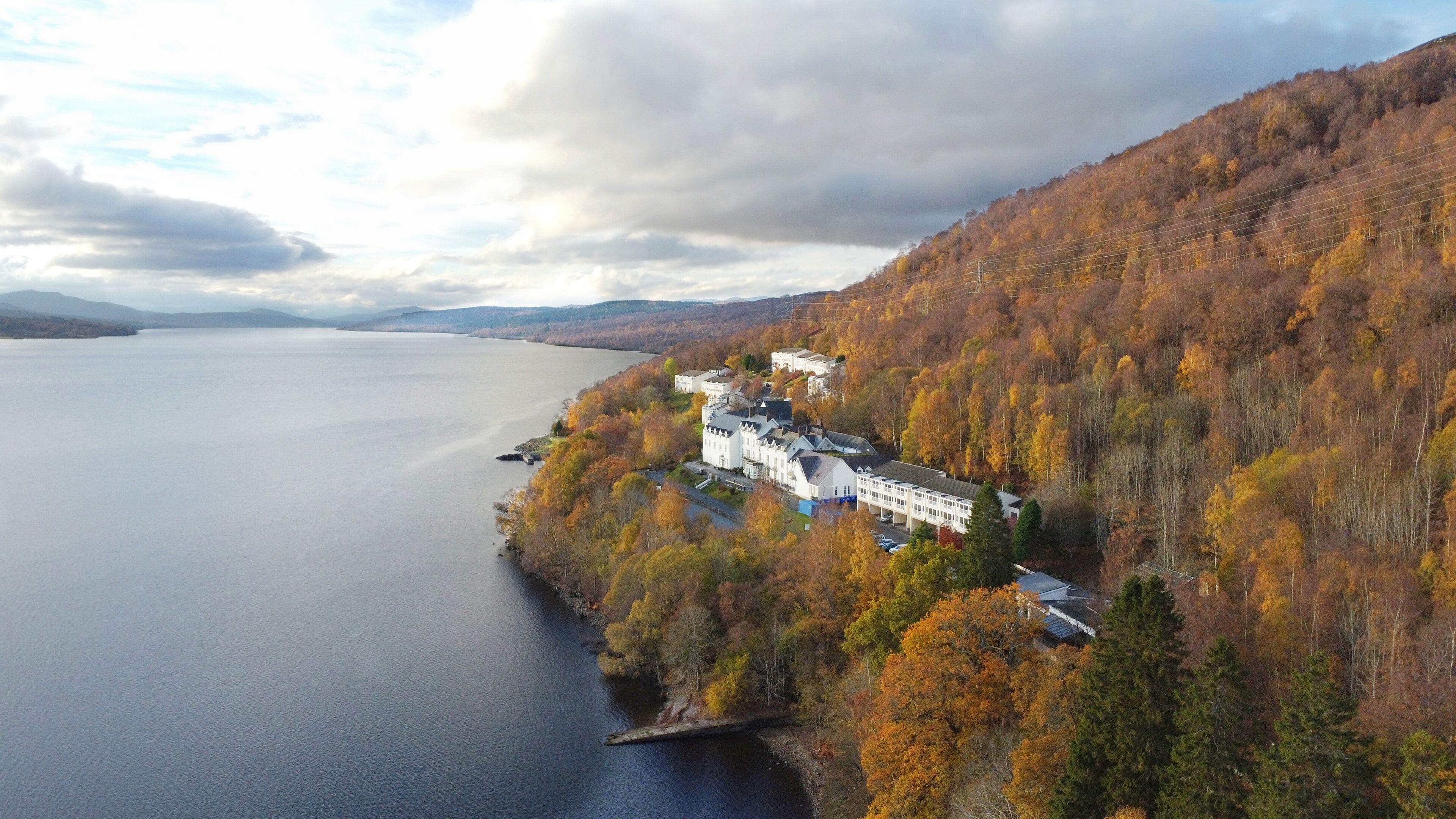 A lakeside property with a large building surrounded by autumn foliage.