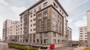 A modern multi-story building with a flat roof, large windows, and a clean, contemporary design. - Stylish Garden View Apartment (Edinburgh)