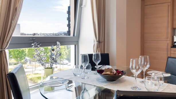 A dining table set with wine glasses, a bowl of fruit, and a vase of flowers. - Stylish Garden View Apartment (Edinburgh)