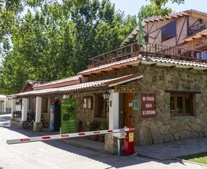 Um edifício de pedra com telhado em telhas, área de recepção e placa indicando ser um camping.