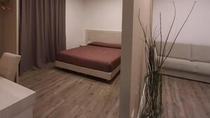 A modern bedroom with a bed, a seating area, and a wardrobe. - B&B Lei (Foggia)