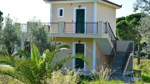 A two-story building with a balcony and a staircase. - Koukounaries Studios (Kefalonia)