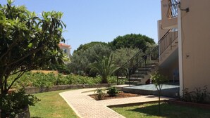 A paved walkway leading to a building with a staircase. - Koukounaries Studios (Kefalonia)