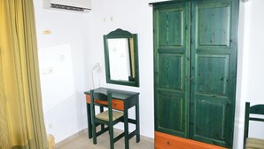 A room with a desk, chair, wardrobe, and an air conditioning unit. - Koukounaries Studios (Kefalonia)