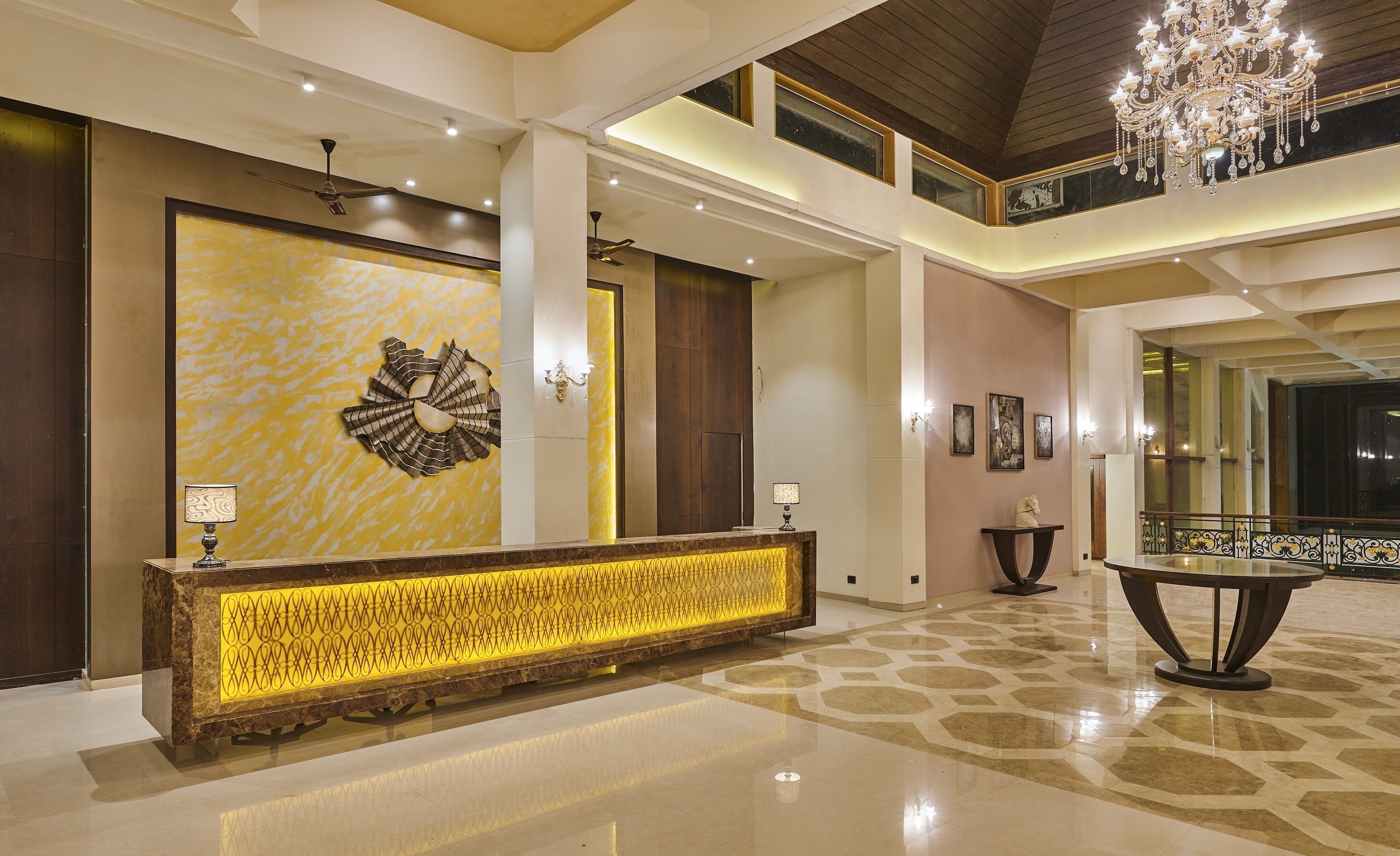 A spacious lobby with a marble reception desk, a chandelier, and artwork on the walls.