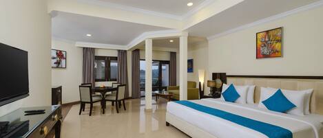 Habitación de hotel con una cama grande, un escritorio, un televisor y vistas al exterior.