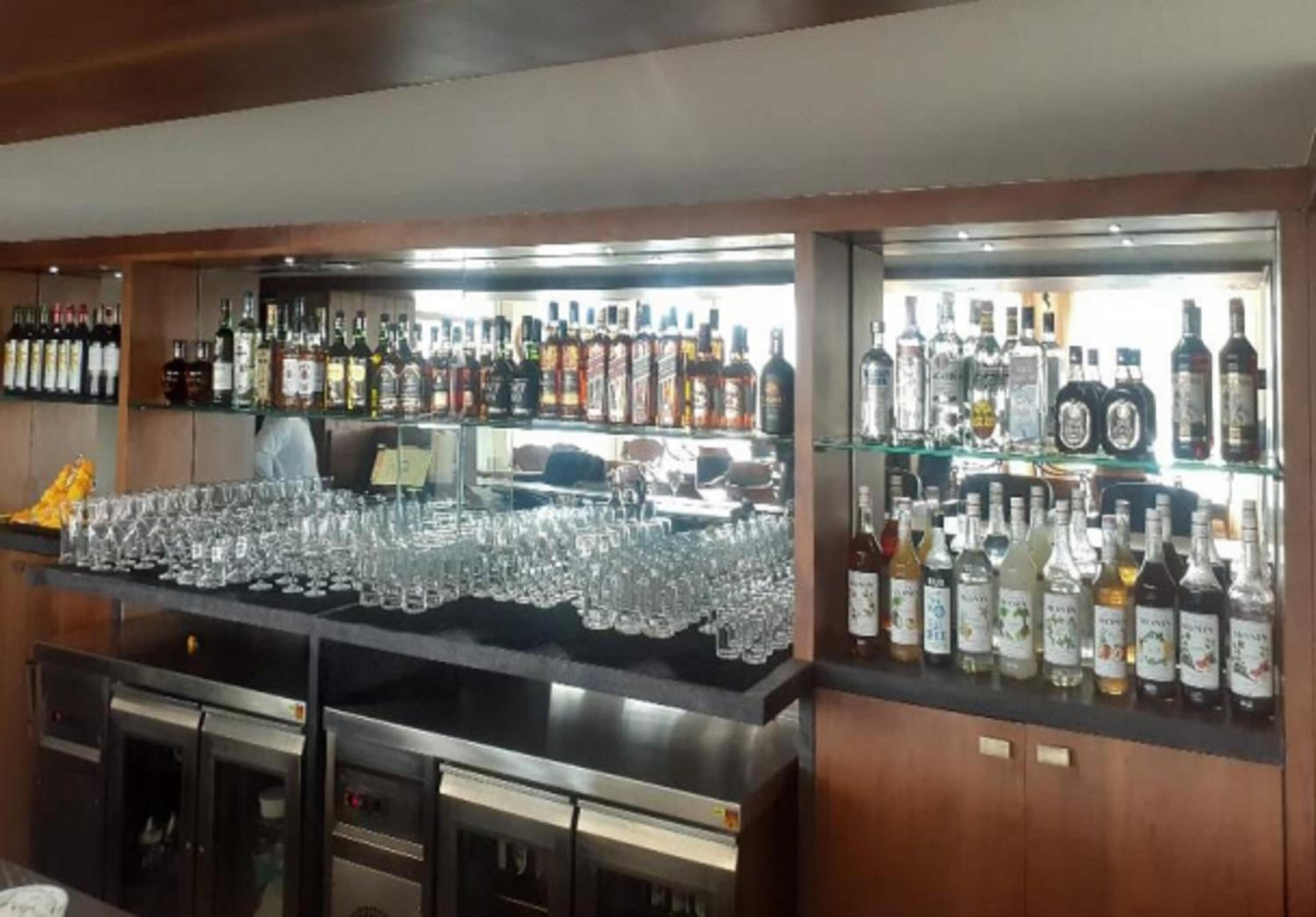 A bar area with shelves of liquor bottles and a counter with glasses.