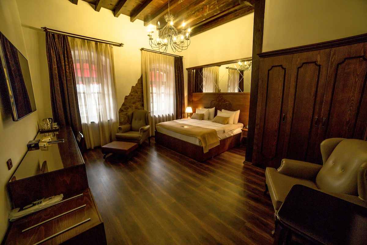 A bedroom with a bed, a chair, a desk, and a mirror.