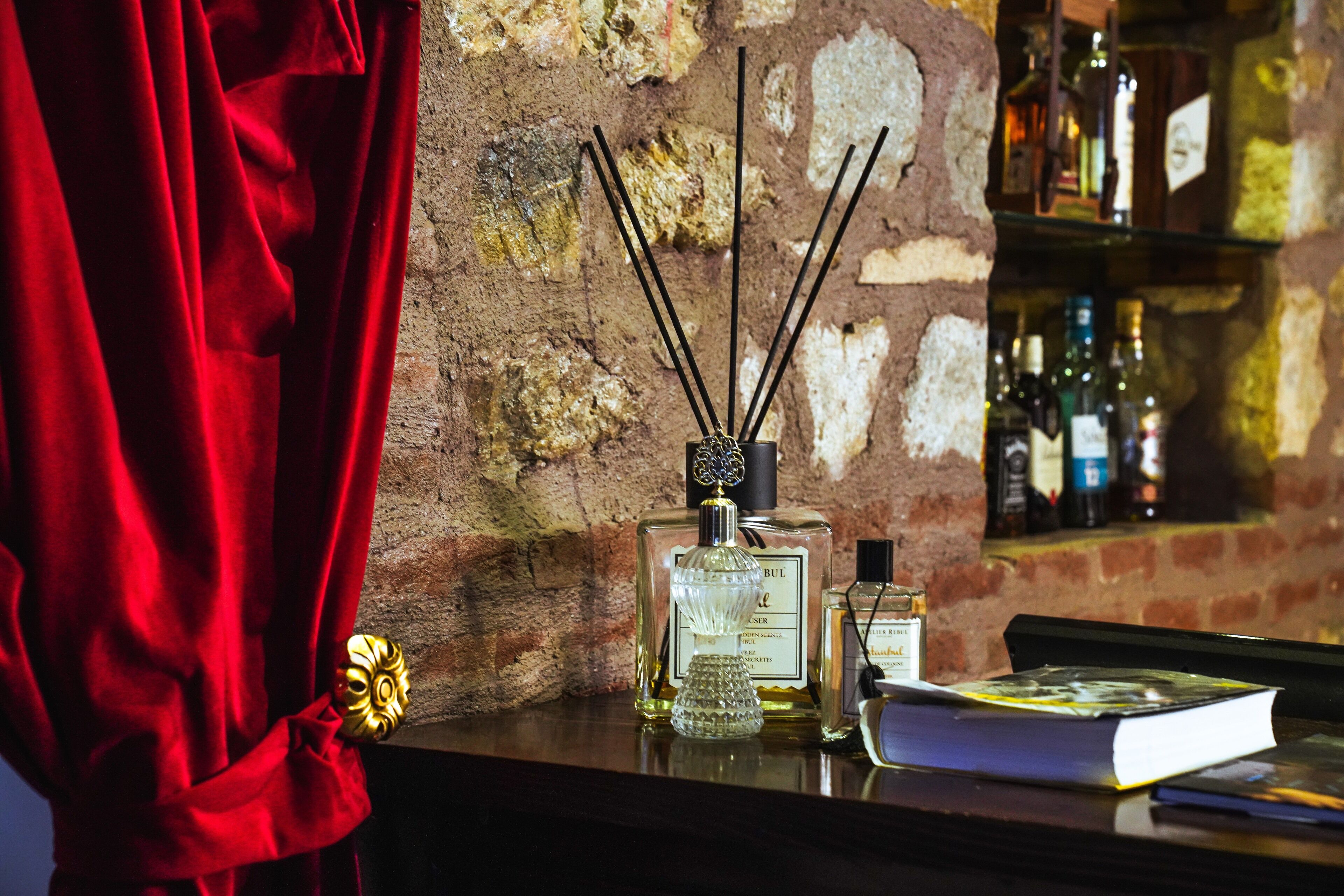 A bar area with a brick wall, a red curtain, and bottles of alcohol.