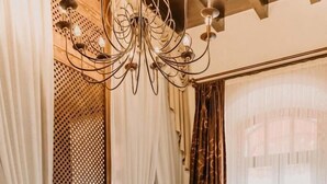 A room with a wooden floor, a sofa with a patterned cushion, a table with candles, and a chandelier. - Panderma Port Hotel (Bandirma)