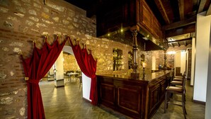 A bar area with a stone wall, wooden bar counter, and red curtains. - Panderma Port Hotel (Bandirma)