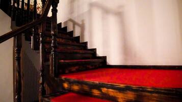 Una escalera de madera con peldaños cubiertos de alfombra roja y una barandilla.