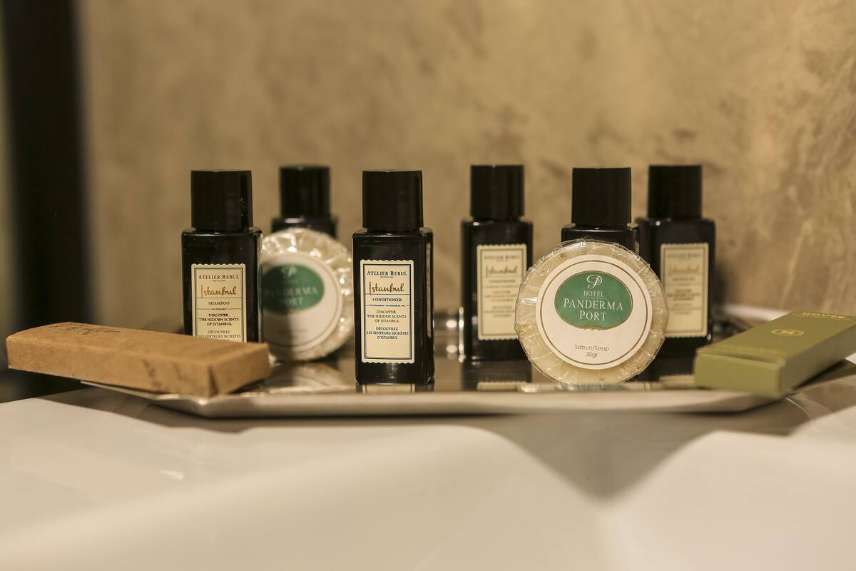 A tray with various toiletries including a bar of soap, bottles of shampoo, conditioner, and a round soap dish.