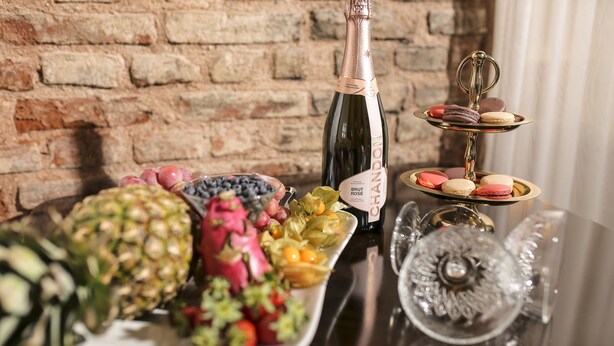 A table with a bottle of Brut Rose champagne, a plate of assorted fruits, and a tiered stand with macarons. - Panderma Port Hotel (Bandirma)