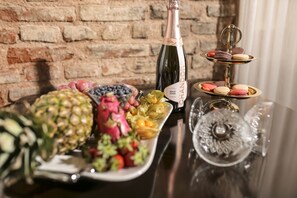 A table with a bottle of Brut Rose champagne, a plate of assorted fruits, and a tiered stand with macarons. - Panderma Port Hotel (Bandirma)