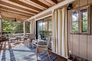 Un espace extérieur abrité, aménagé avec une table, des chaises et un tapis à motifs.