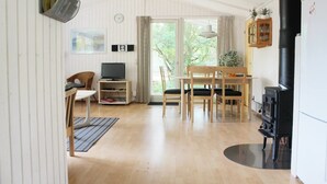 A cozy living room with a TV, wooden furniture, and a fireplace. - Holiday home Aakirkeby (Akirkeby)