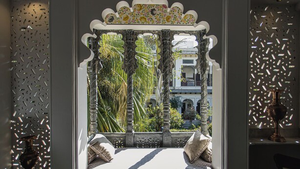 A room with a view of a building through a decorative window with a patterned frame. - Kintsugi at Rangniwas (Udaipur)