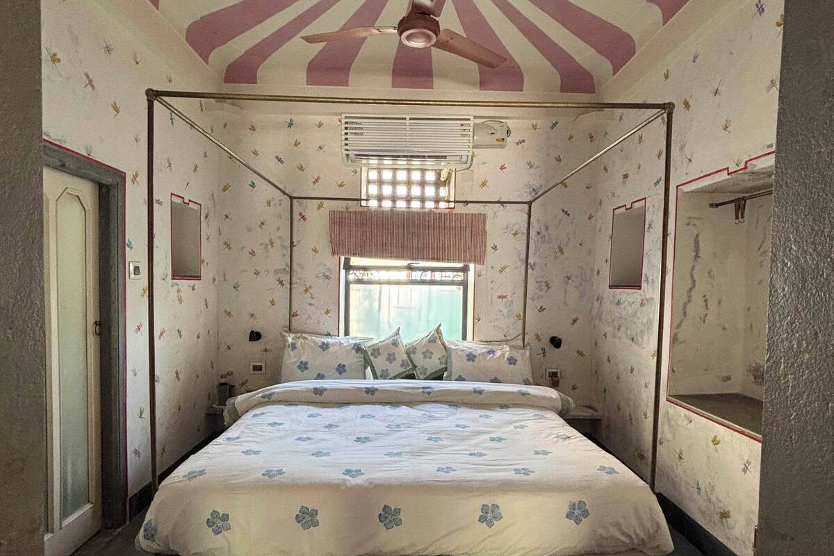 A bedroom with a bed, a ceiling fan, a window with curtains, and a radiator.