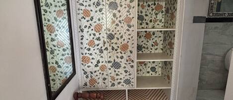 A bathroom with a mirror, a bench, a patterned rug, and a tiled wall with floral designs.