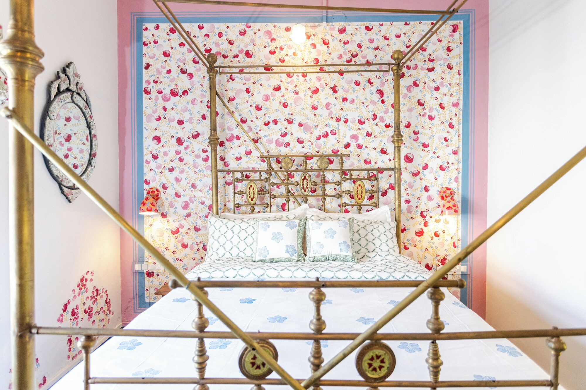 A four-poster bed with a floral-patterned headboard and a white bedspread with blue floral accents.