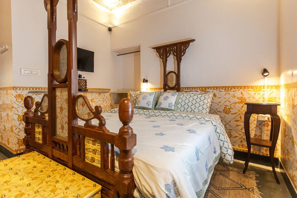 A traditional room with a wooden bed, a small table, and a chair.