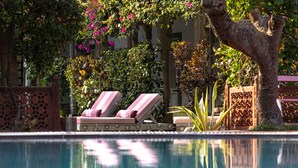 A pool area with lounge chairs and a decorative tree. - Kintsugi at Rangniwas (Udaipur)