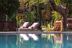 Una piscina al aire libre, sombrillas, sillones reclinables de piscina