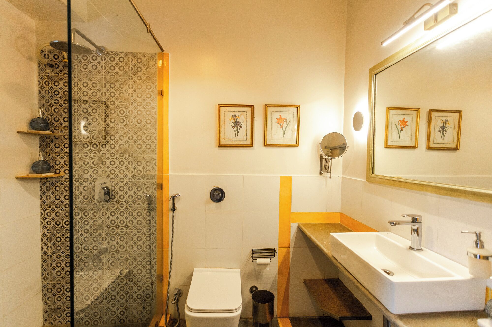 A bathroom with a shower, toilet, sink, and framed floral artwork on the wall.
