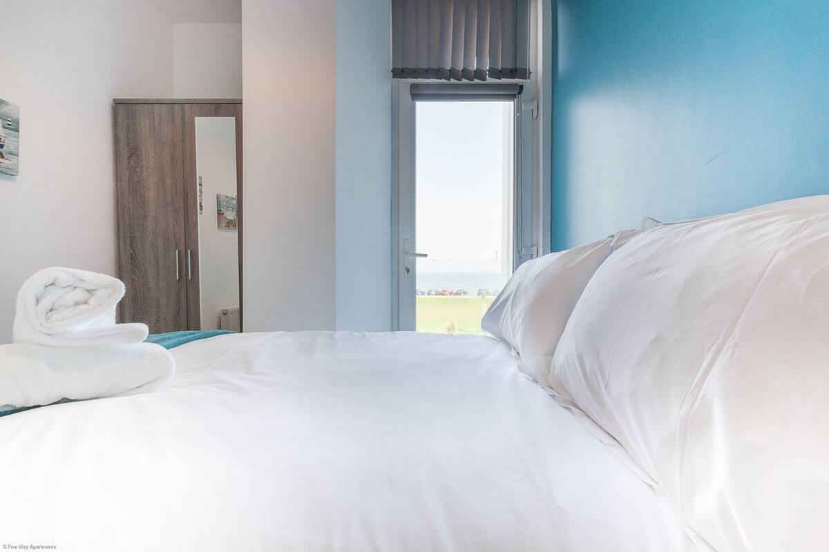 Quarto de hotel com cama, janela com cortinas, porta e toalha na cama.