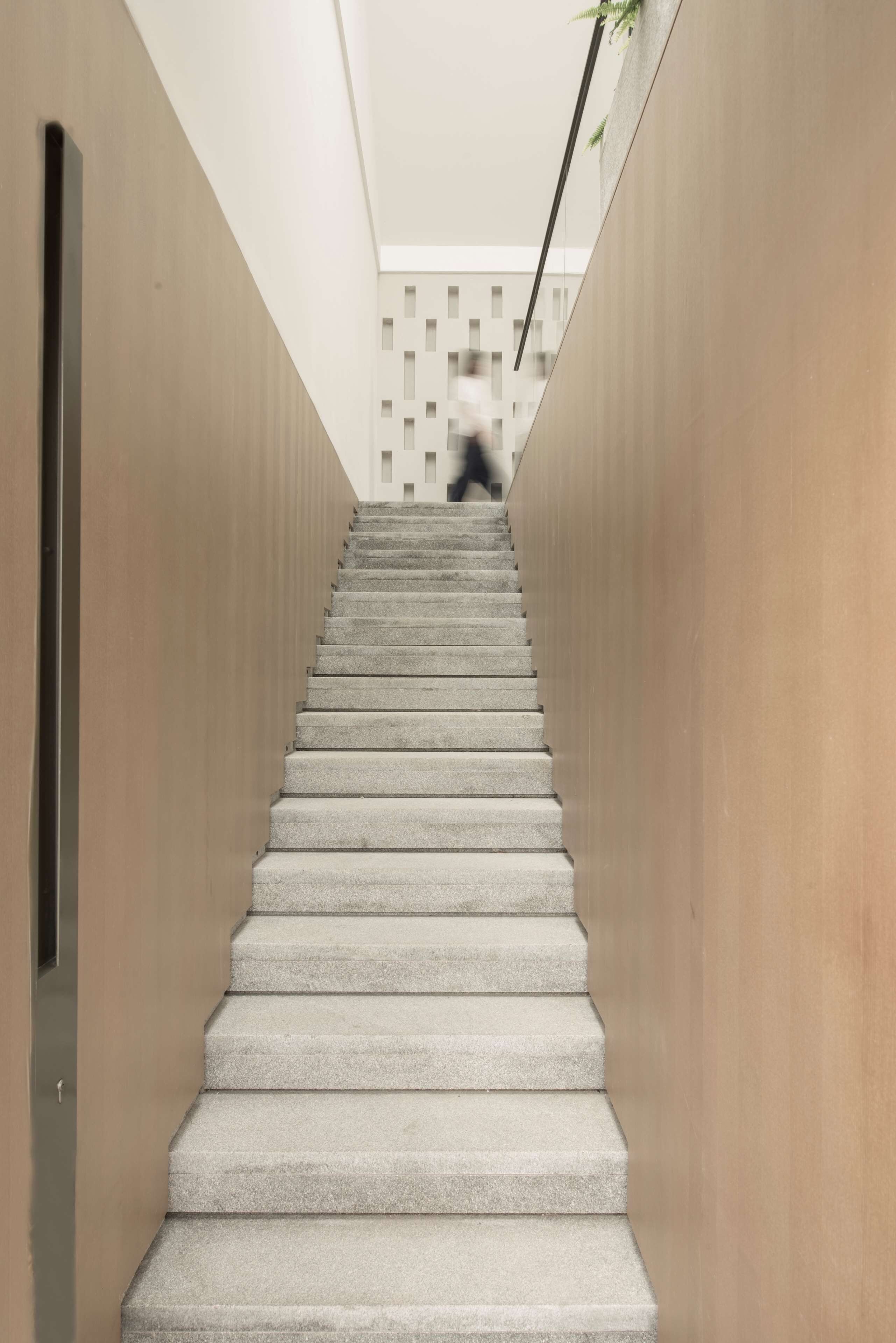 Una escalera moderna con un diseño minimalista que lleva a un edificio de fachada geométrica.
